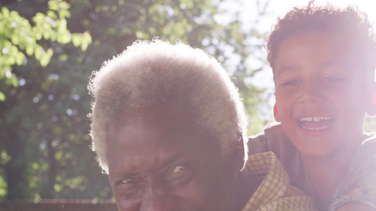 Senior black man with grandson riding on his back, close up