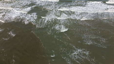 Aerial-view-of-waves-washing-onto-a-sandy-shore