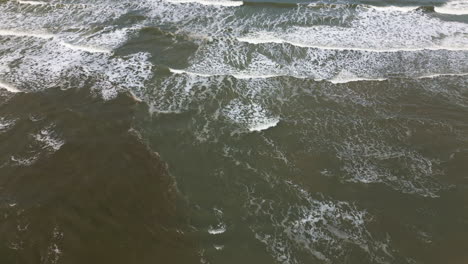 aerial view of waves washing onto a sandy shore