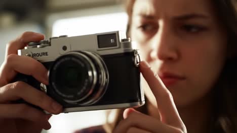a young woman carefully examines her vintage camera while preparing to capture unique urban scenes. her concentration reflects her passion for photography, set against a lively city backdrop.