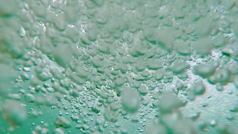 jumping into underwater bubbles in clear blue lake and swim up to air, pov moving through dense cloud of soft focus bubbles toward bright shining summer day sun