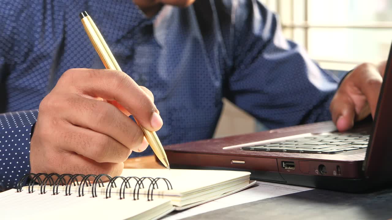 persona que trabaja en una computadora portátil y toma notas