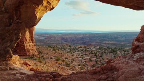 Paisaje-Desértico-Visto-A-Través-Del-Agujero-Del-Arco-De-Piedra-Arenisca-Natural-En-El-Parque-Nacional-Arches-En-Utah,-Estados-Unidos