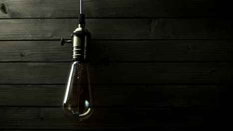 the light bulb slowly lights up, quickly flickers on a background from a wood