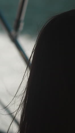 silhouette of long-haired woman on background of blurred foaming water closeup. calm young lady looks at sea surface thoughtfully standing on boat backside view slow motion