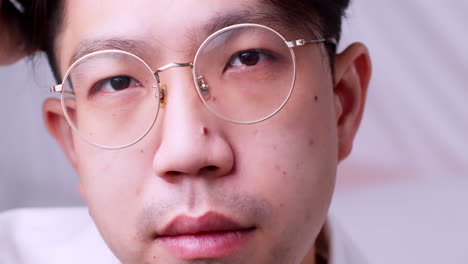 Close-up-Asian-man-with-glasses-and-healthy-good-hair-looking-to-the-camera-and-spoiling-himself-by-tidying-his-hair