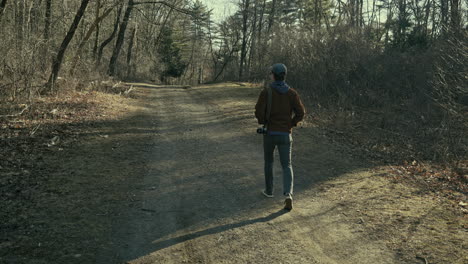 young photographer walks down a forest trail