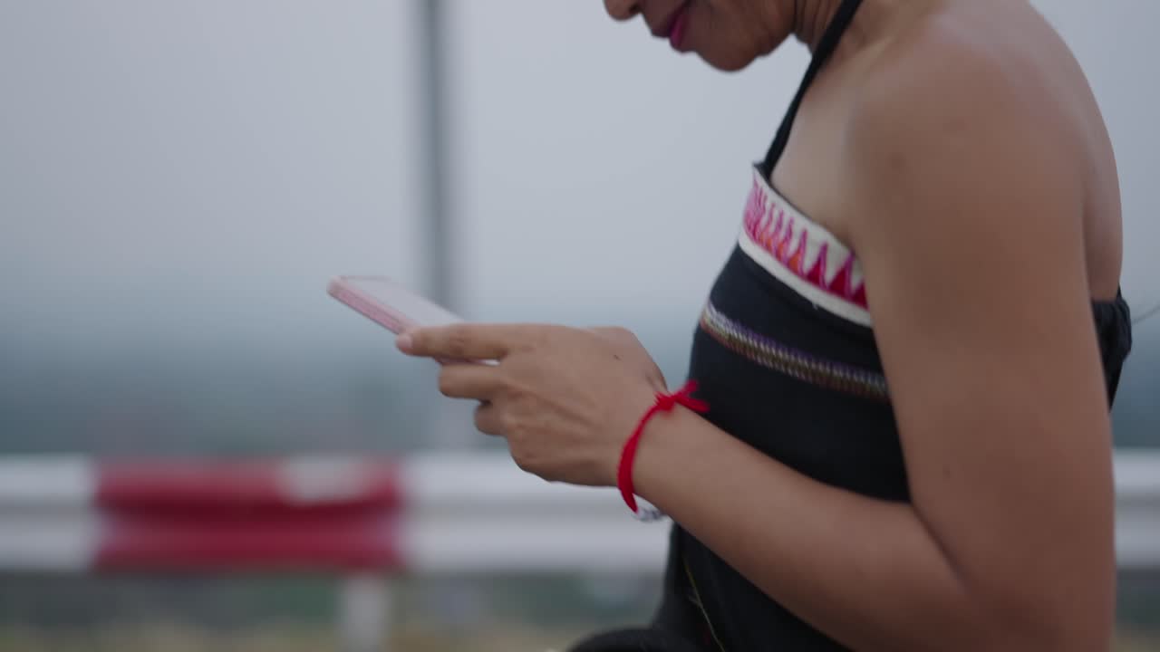Close-up of a person's hands using a smartphone outdoors in a misty environment