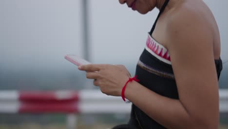 close-up of a person's hands using a smartphone outdoors in a misty environment