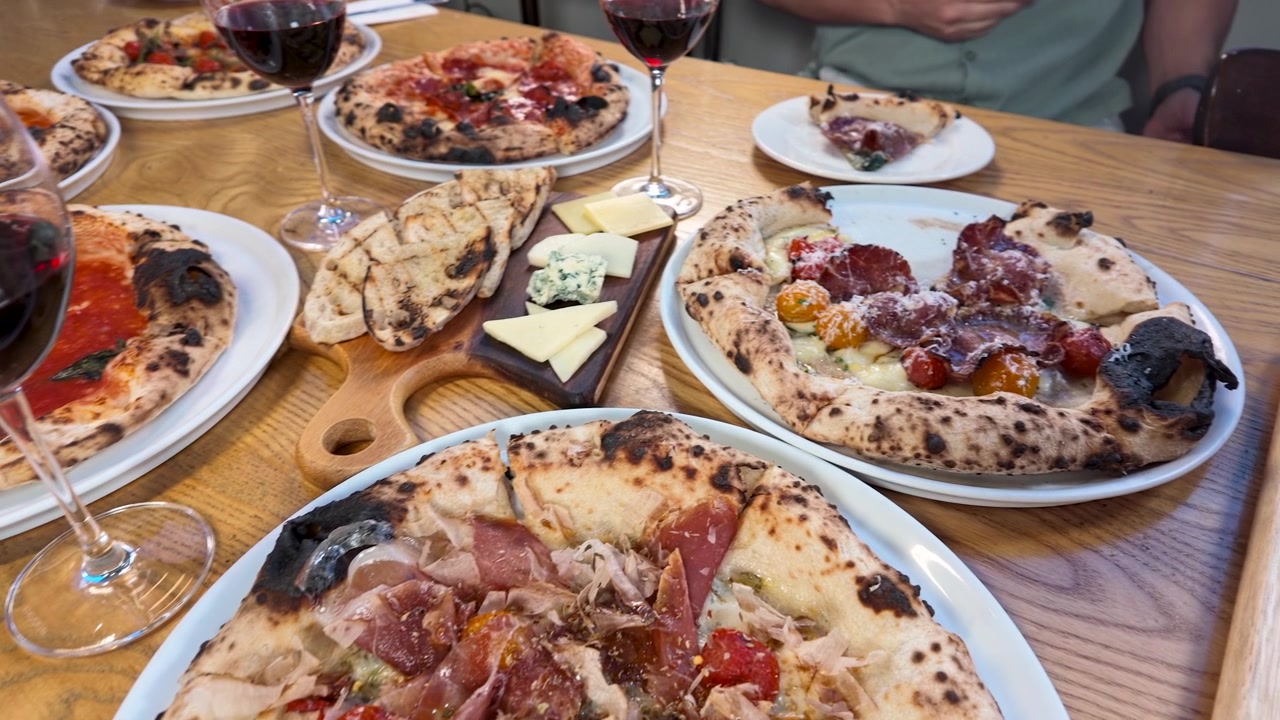 Freunde genießen Gourmet-Pizza und Rotwein an einem Restauranttisch