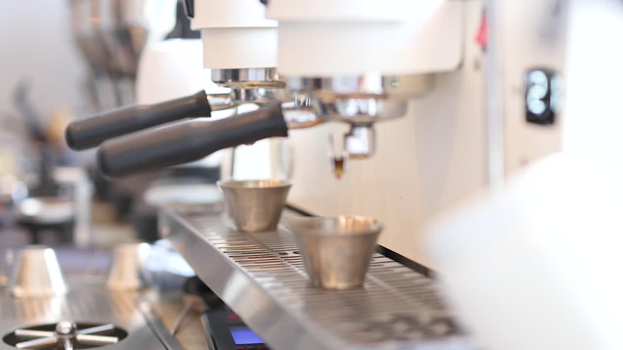 A barista operates an espresso machine in a bright cafe, capturing the coffee-making process with precision and focus