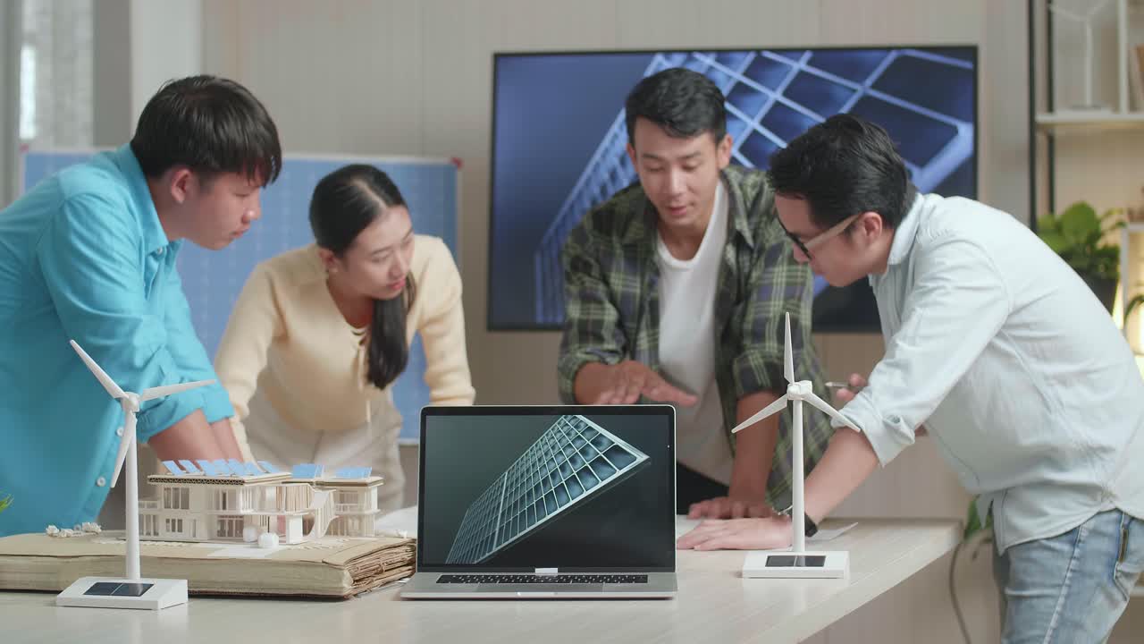 테이블 위의 노트북은 아시아 엔지니어 그룹이 사무실에서 블루프린트 작업에 대해 논의하는 동안 태양전지를 보여줍니다.