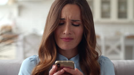 Sad business woman looking mobile phone at home office. Girl checking phone.