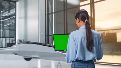 mujer trabajando en una computadora portátil en una oficina moderna con un dron