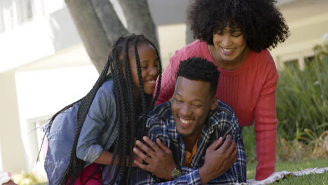 Happy-african-american-parents-with-daughter-lying-on-blanket-in-garden-at-home,-slow-motion