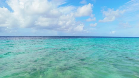 Low-aerial-dolly-above-sandy-coral-reef-to-ocean-drop-off-with-dark-deep-blue-water