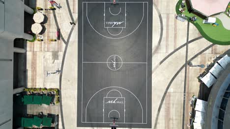 modern mega shopping mall with a basketball court inside from drone's eye view