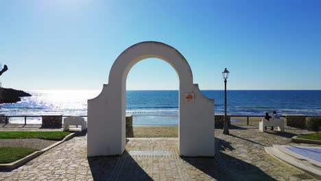 la ciudad costera soleada de gaeta, lazio, dolly aérea a través del arco blanco sobre la playa de arena y el agua del océano