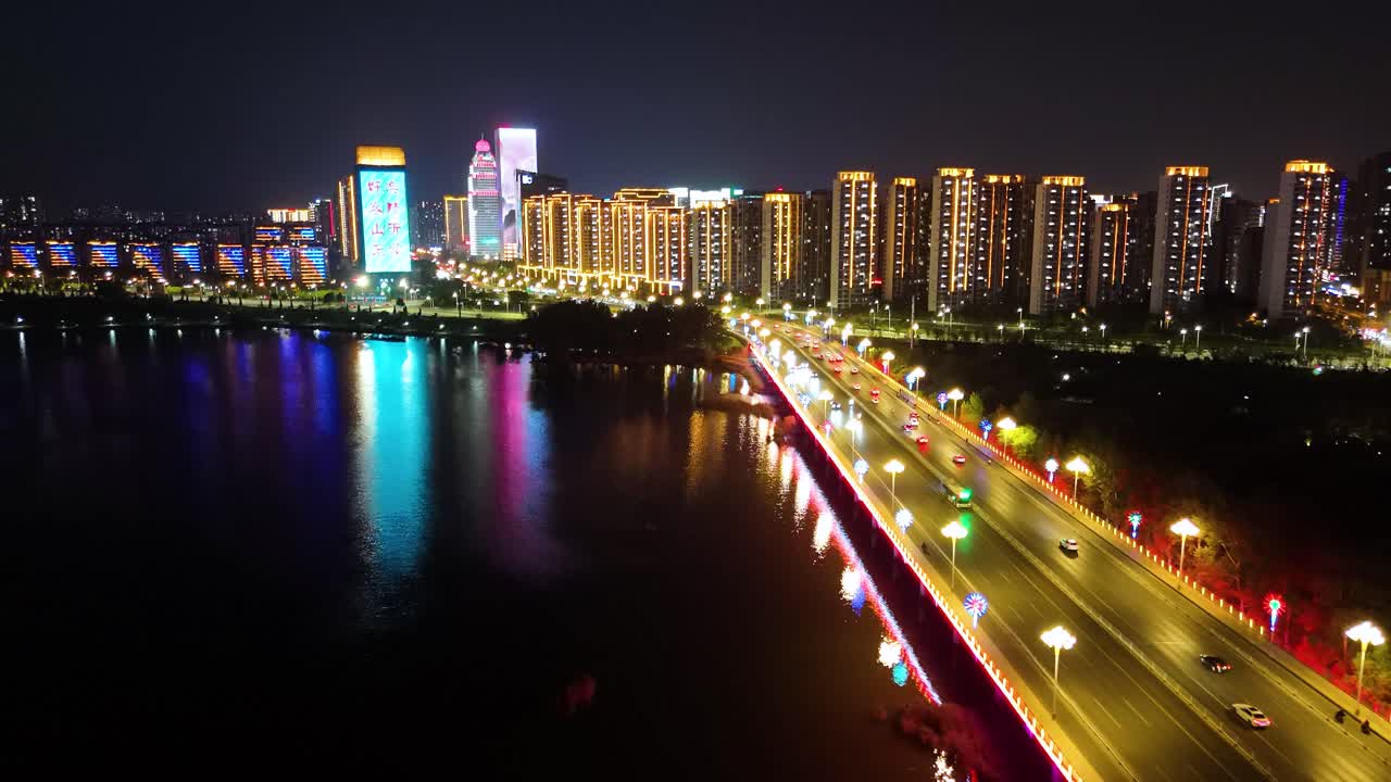 vista aérea nocturna de edificios iluminados cerca de la orilla del río en la ciudad de linyi, provincia de shandong