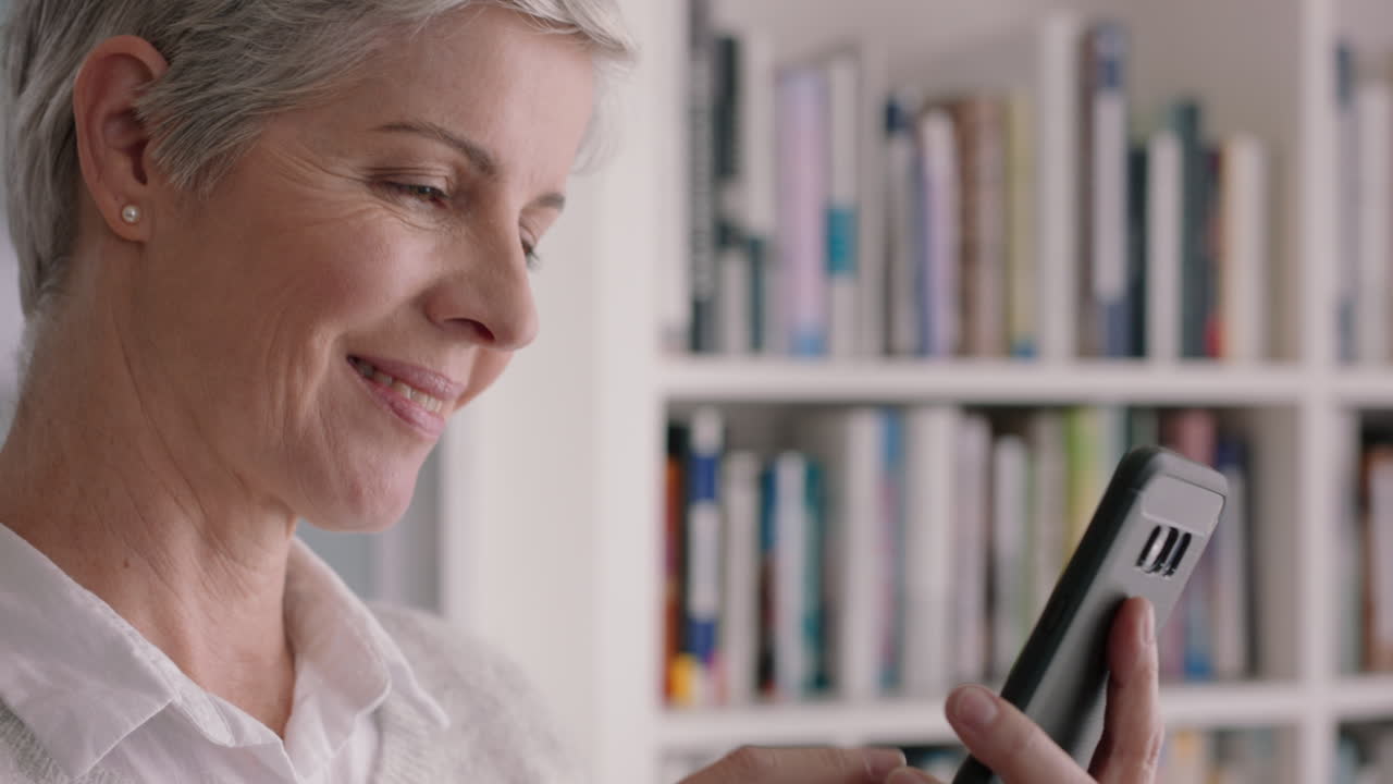 mujer madura feliz usando un teléfono inteligente enviando mensajes de texto navegando por las redes sociales leyendo mensajes de texto disfrutando de la comunicación digital en el teléfono móvil imágenes 4k
