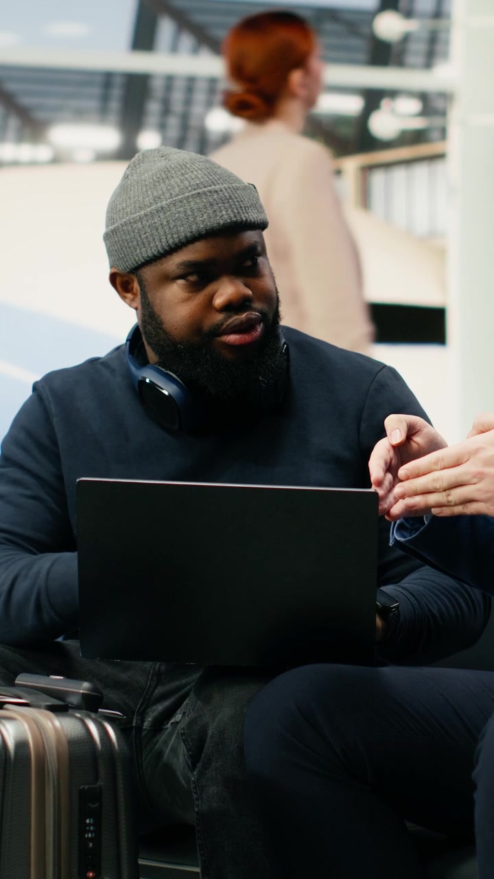 Vertical Video Manager and assistant with laptop in airport preparing for meeting abroad