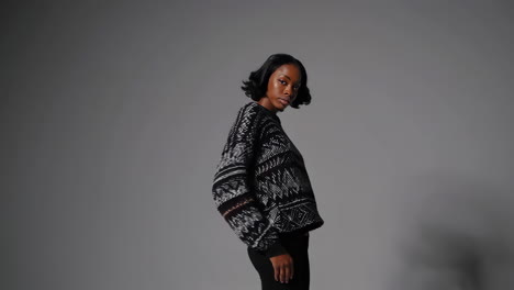 stylish black woman posing in a patterned sweater in a studio