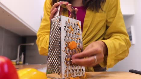 woman grating carrots in a kitchen