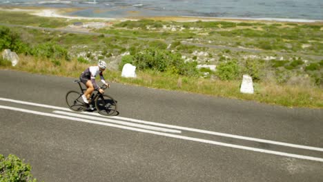 female cyclist cycling on a coastal road 4k