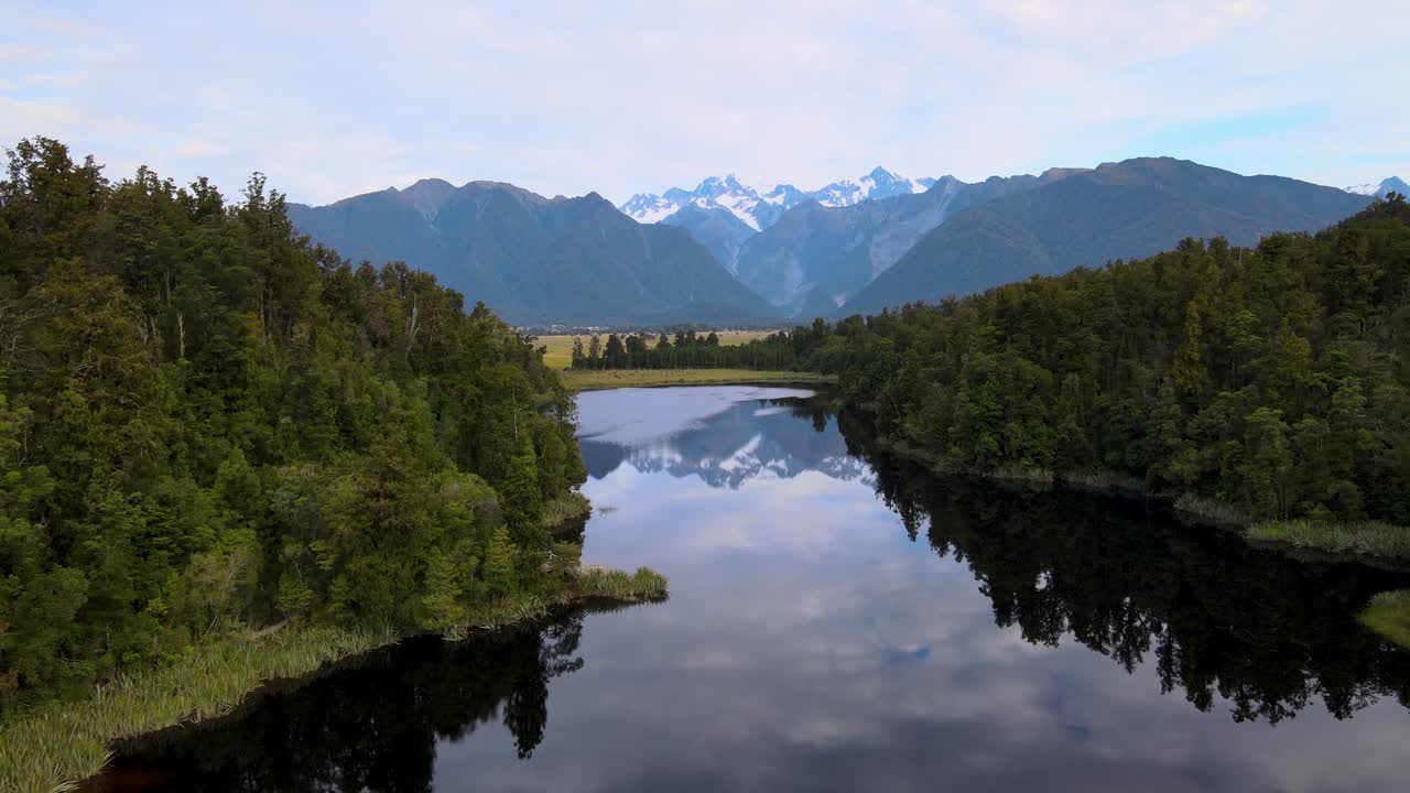 Høye snødekte fjelltopper på New Zealand speiles i stille vann i Lake Matheson, Fox Glacier