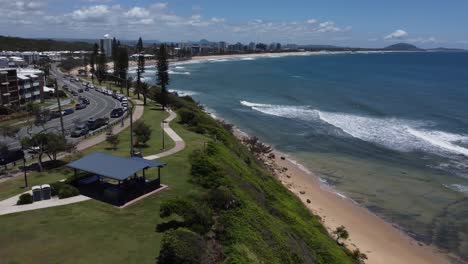 Vista-Aérea-De-La-Costa-Y-La-Playa-Con-Un-Pequeño-Pueblo-Al-Fondo