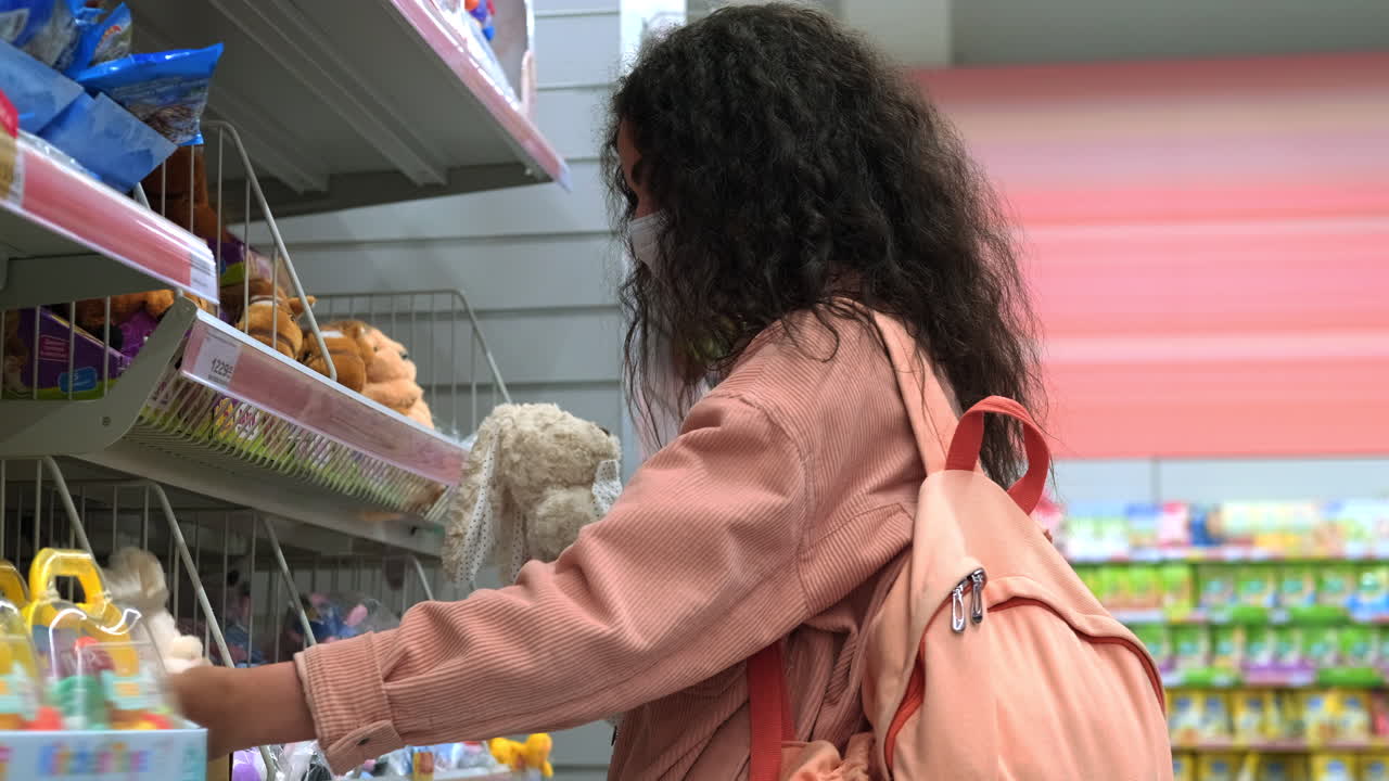 una mujer comprando juguetes en una tienda con una máscara.