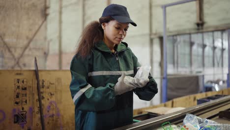 afro american girl sorting bottles at a garbage recycling plant. pollution control