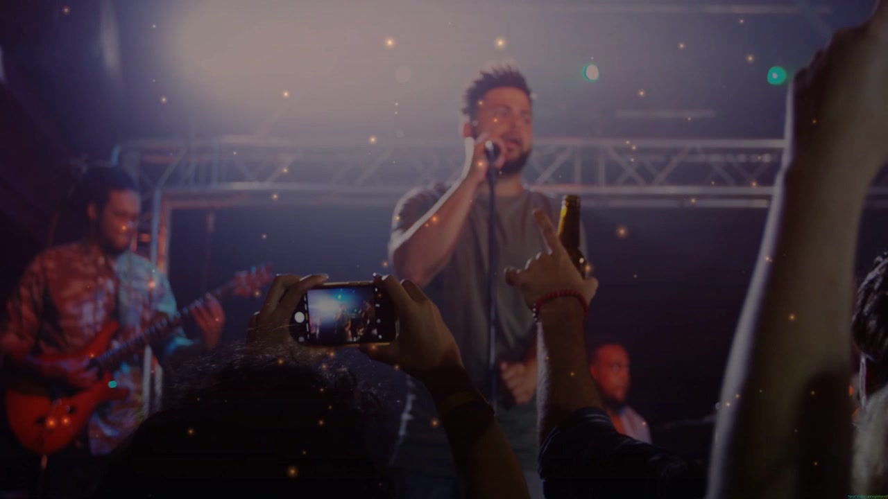 Cantante solista che canta al microfono e fan che alzano gli smartphone filmando la band musicale sotto una luce controluce diffusa