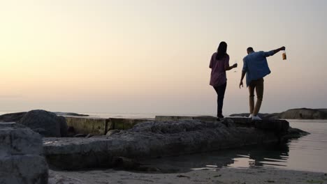 Rückansicht-Eines-Gemischtrassigen-Paares,-Das-Bei-Sonnenuntergang-Am-Strand-Spaziert,-4k