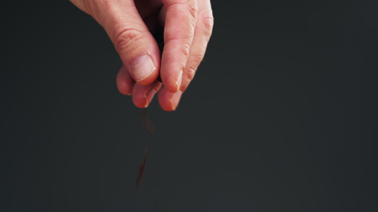 Carnation spice on spoon macro close-up. Man hand strewing dry cloves. Selective focus.Spice for food and drinks. High quality 4k footage