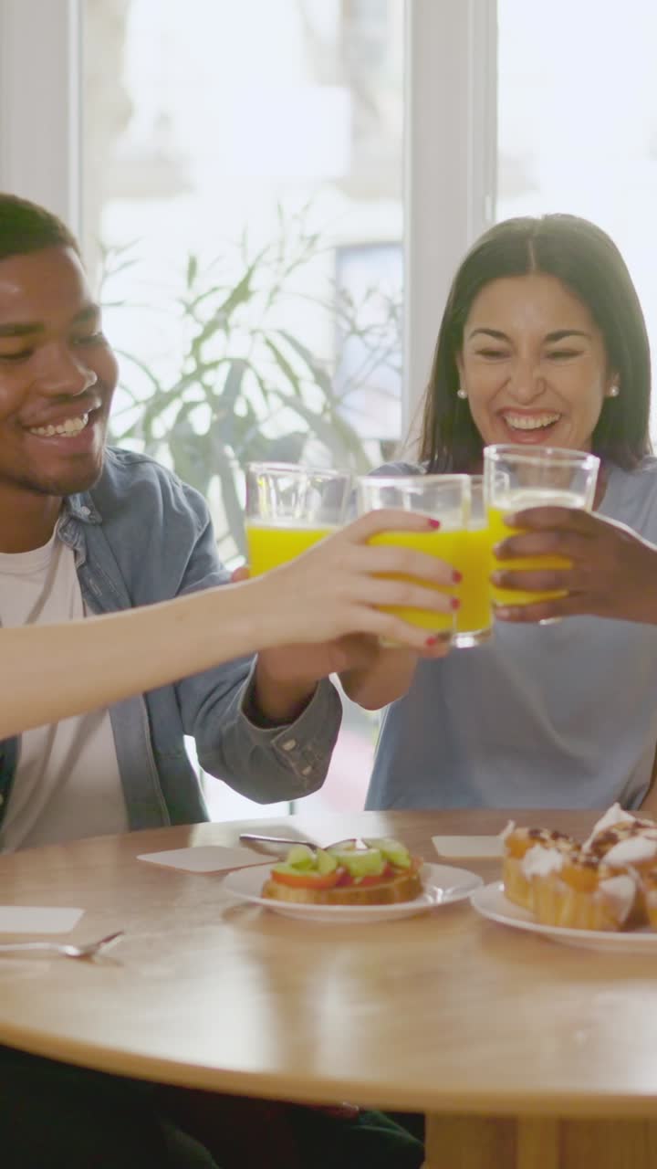 Friends toasting with orange juice at breakfast