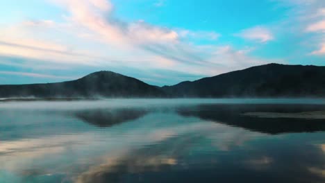 view of a misty lake reflecting the sunrise colors of the sky