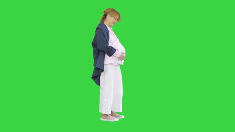 pregnant woman caressing her belly on a green screen, chroma key