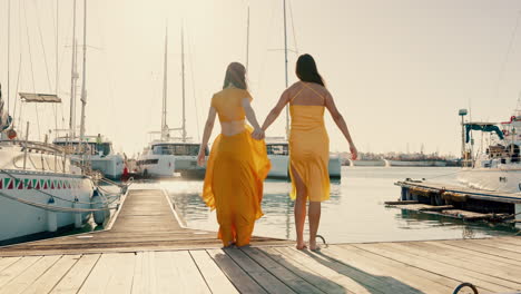 back, happy and women holding hands at a harbor