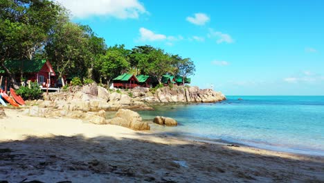 beach cabins on beautiful rocks and sandy beach on shore of tropical island with lush vegetation, washed by calm blue sea in myanmar