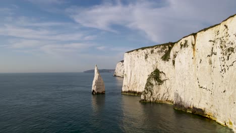 Aerial-drone-forward-between-stack-and-rocky-cliff-wall-of-Old-Harry-Rocks,-Dorset