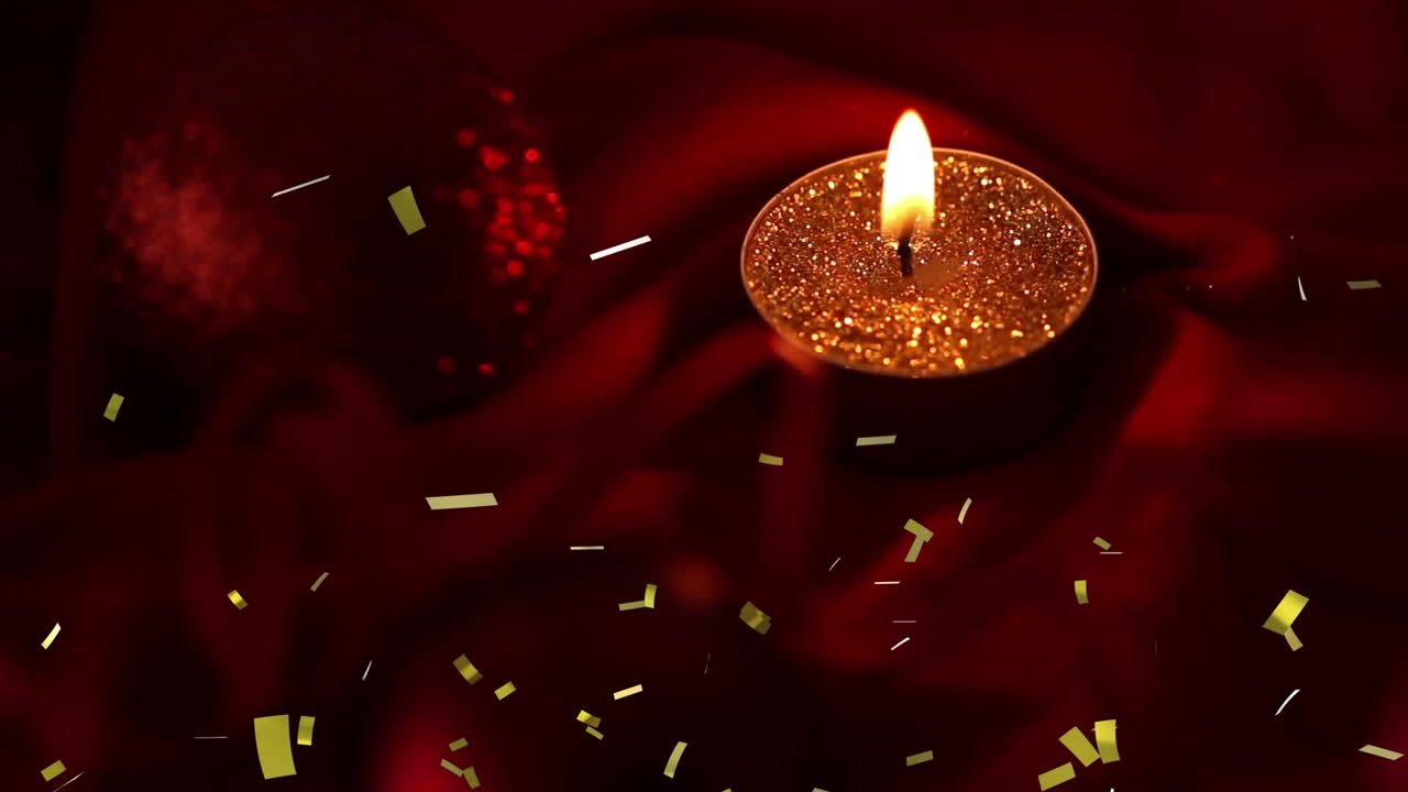 Animazione di coriandoli dorati che cadono su una candela tea light accesa su sfondo scuro