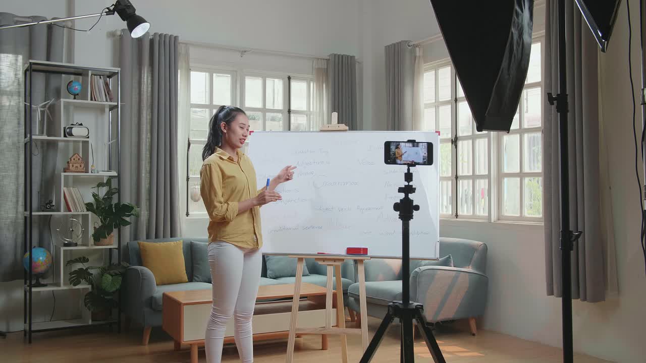 Asian Female Teacher With Marker Pen Shoots Video By Smartphone Camera While Teaching English At Home