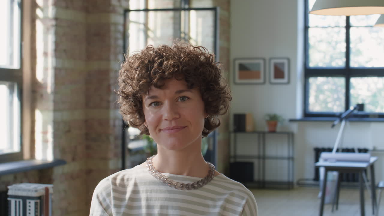A woman with curly hair smiling in a modern office