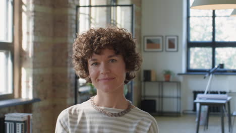 a woman with curly hair smiling in a modern office