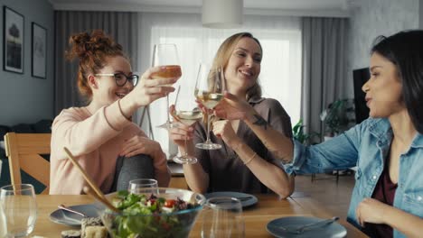 three female caucasian friends chatting and drinking wine at home