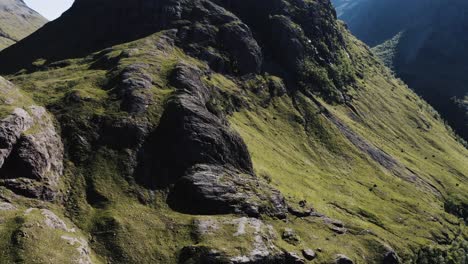 Disparo-De-Un-Dron-Inclinándose-Hacia-Arriba-Para-Revelar-Un-Pico-Alto-En-El-Valle-De-Glenco,-Escocia