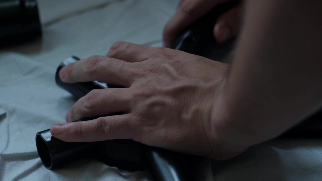 Primo piano di mani che assemblano la base di una sedia da gaming all'interno, usando componenti metallici e viti durante il montaggio di mobili.