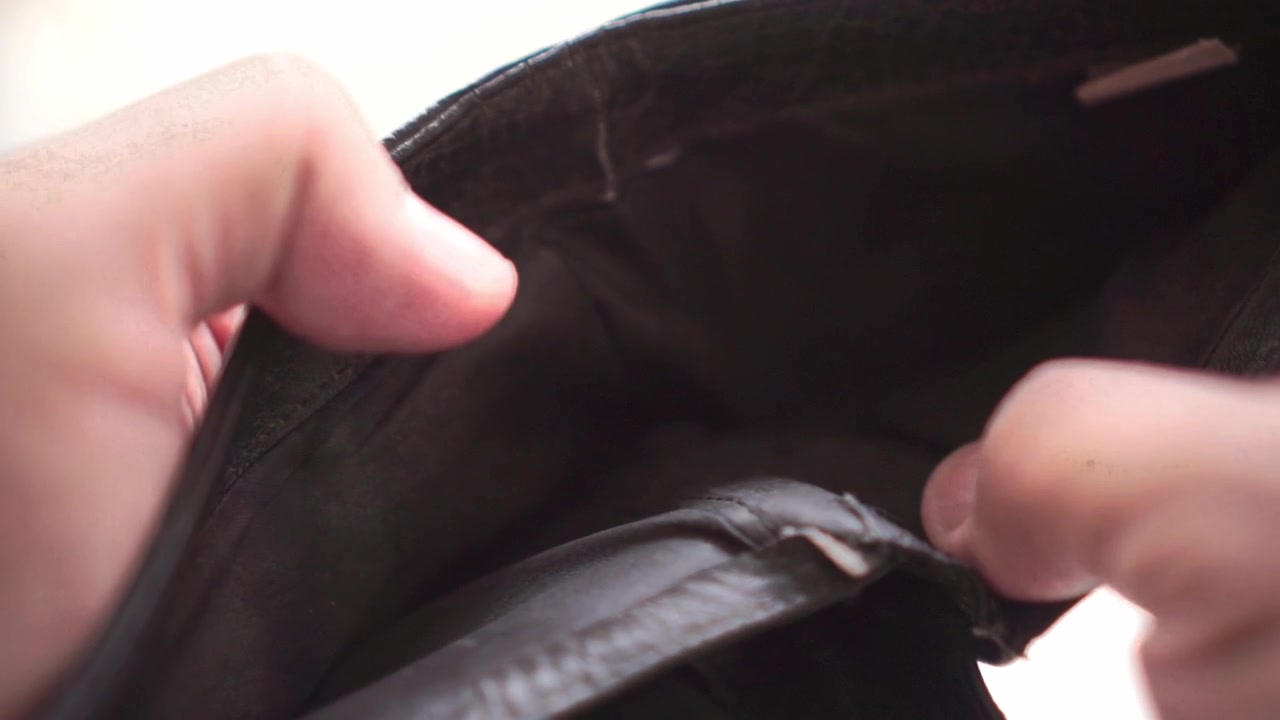 Hände öffnen eine leere Brieftasche, was finanzielle Not, Geldmangel, persönliche Budgetplanung, wirtschaftliche Herausforderungen und Bargeldknappheit thematisiert.
