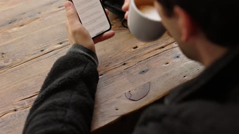 hombre usando el teléfono y bebiendo café en una cafetería